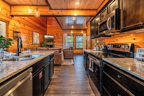 A modern kitchen with granite countertops, stainless steel appliances, and a wooden interior. - Just Remodeled Cabin w/ 4-Game Arcade, Hot Tub & Peloton | 4 Mi to Dollywood! (Pigeon Forge)