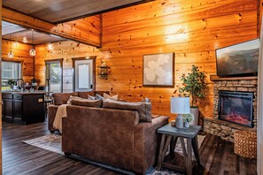 Un intérieur de chalet chaleureux comprenant un espace de vie, une cuisine et une cheminée.