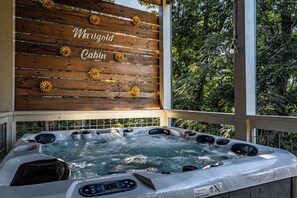 A hot tub with a wooden cabin sign above it, surrounded by greenery. - Just Remodeled Cabin w/ 4-Game Arcade, Hot Tub & Peloton | 4 Mi to Dollywood! (Pigeon Forge)