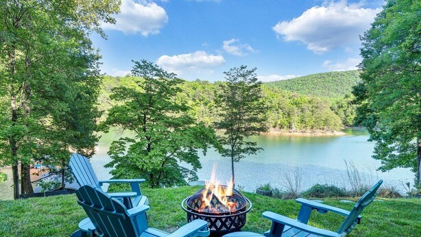 Vista del lago con un brasero y sillas Adirondack.