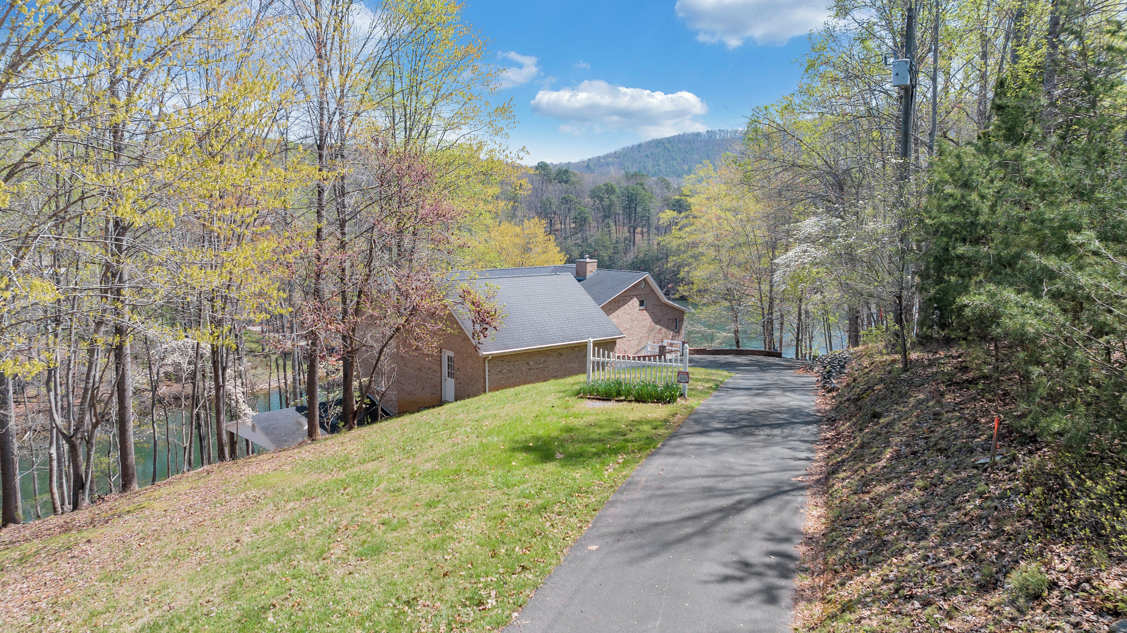 A residential area with houses, a paved driveway, and a lake.