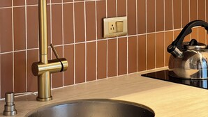 Una cocina con un grifo moderno, una tetera y un salpicadero de azulejos.