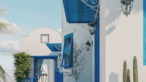 Un edificio blanco con detalles azules, una escalera y un cactus.