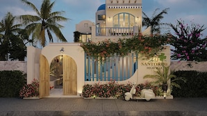 Una villa con una amplia entrada en arco, un balcón y un cartel que indica 'SANTORINI HOI AN VILLA'.