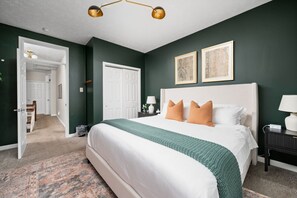 Une chambre à coucher avec un grand lit, une table de chevet avec une lampe et une porte donnant sur une autre pièce.