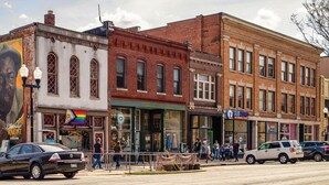A street view with a brick building, a mural, and storefronts including a Sub Zero ice cream shop. - Steps to Mass Ave • Sleeps 9 • Free Parking (Indianapolis)