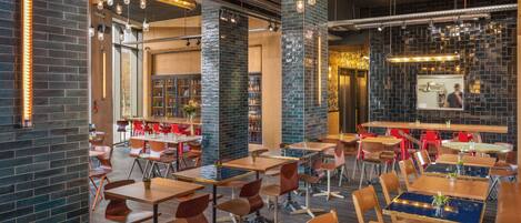 A modern restaurant interior with brick walls, wooden tables, and red chairs.