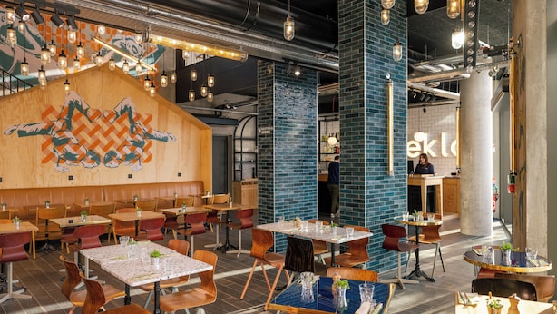 A restaurant interior with multiple dining tables and chairs, a bar area, and a mural on the wall. - Eklo Hotels Montpellier Centre Gare (Montpellier)