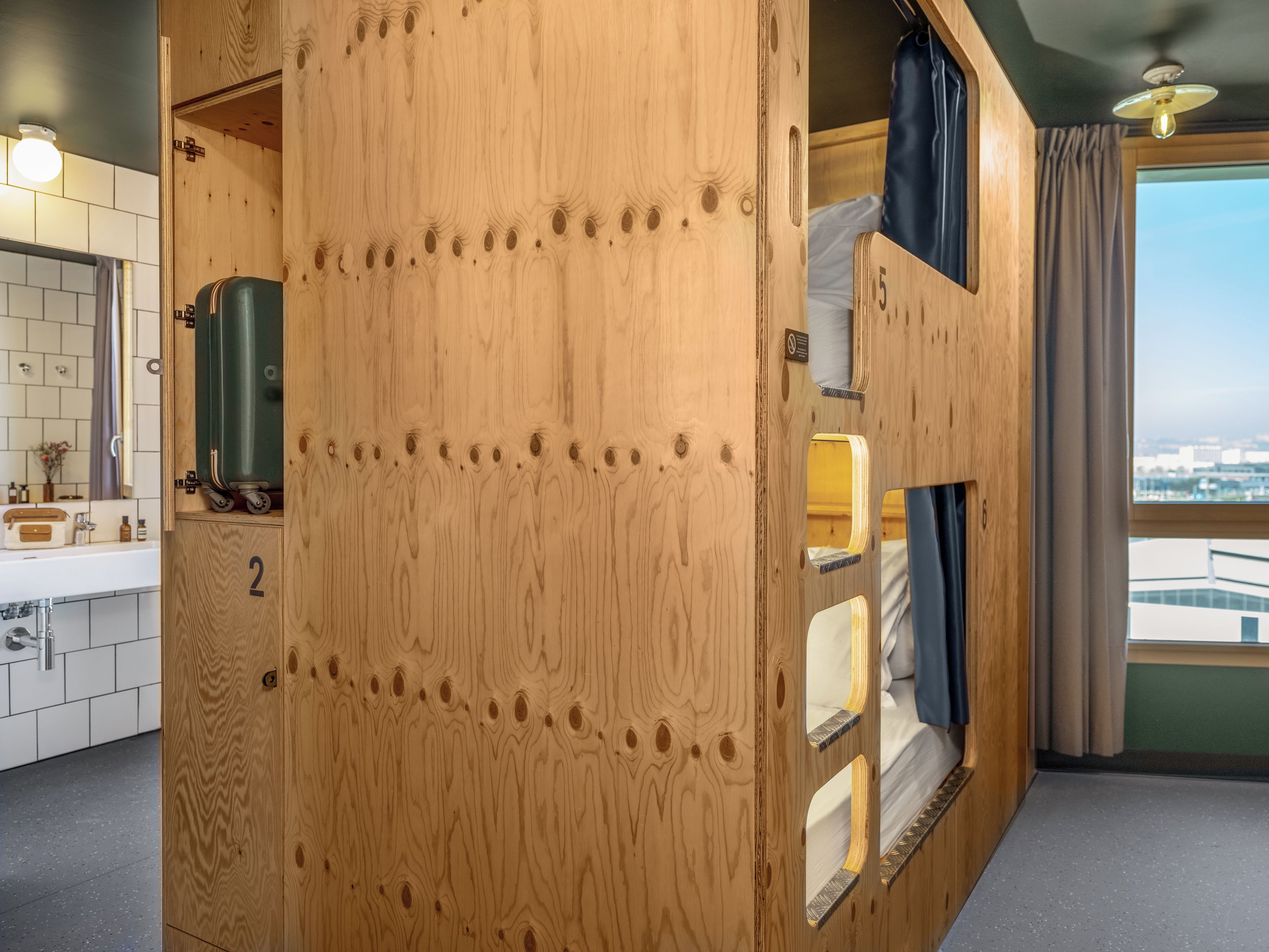 A wooden room with a kitchenette, a bed, and a view of the city.
