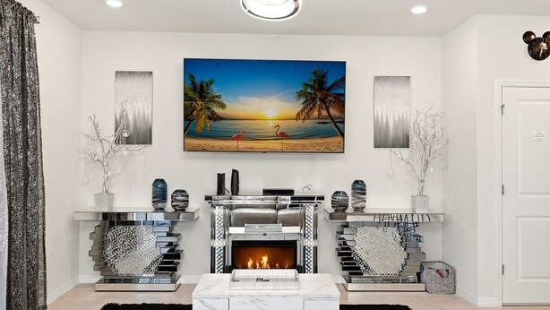 Een moderne woonkamer met een open haard, een groot schilderij van een strand en een trap met een bijzonder ontwerp.