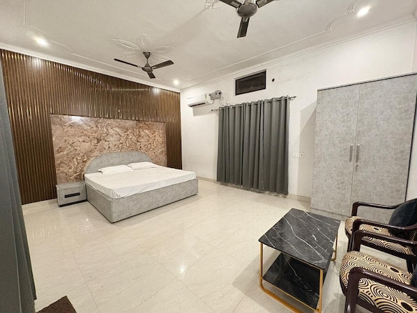 Une chambre à coucher comprenant un lit, un bureau, une chaise, une armoire et un ventilateur de plafond.
