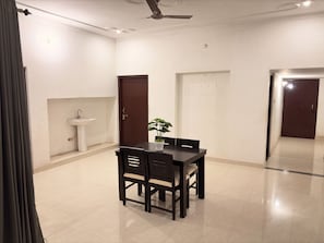Une pièce comprenant une table à manger, des chaises, une plante en pot, un évier et un ventilateur de plafond.