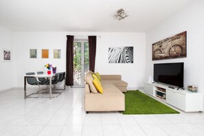 A modern living room with a sofa, TV, and artwork on the wall. - Casa Rosa: Panoramic Balcony Overlooking the Gulf and Vesuvius in the Heart of Sorrento (Sorrento)