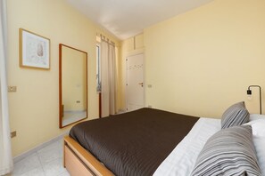Ein Schlafzimmer mit einem Bett, einem Spiegel, einer Tür und einer Lampe.
