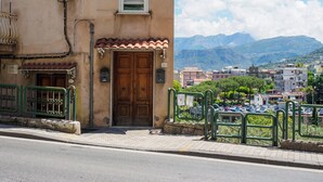 A building with a wooden double door, a small window, and a tiled awning. - Casa Rosa is one of those places you choose for one specific detail… and then remember for everything else. That detail is the view: a balcony opening onto the Gulf of Naples with Mount Vesuvius in front, a wide, deep panorama that accompanies every mo (Sorrento)