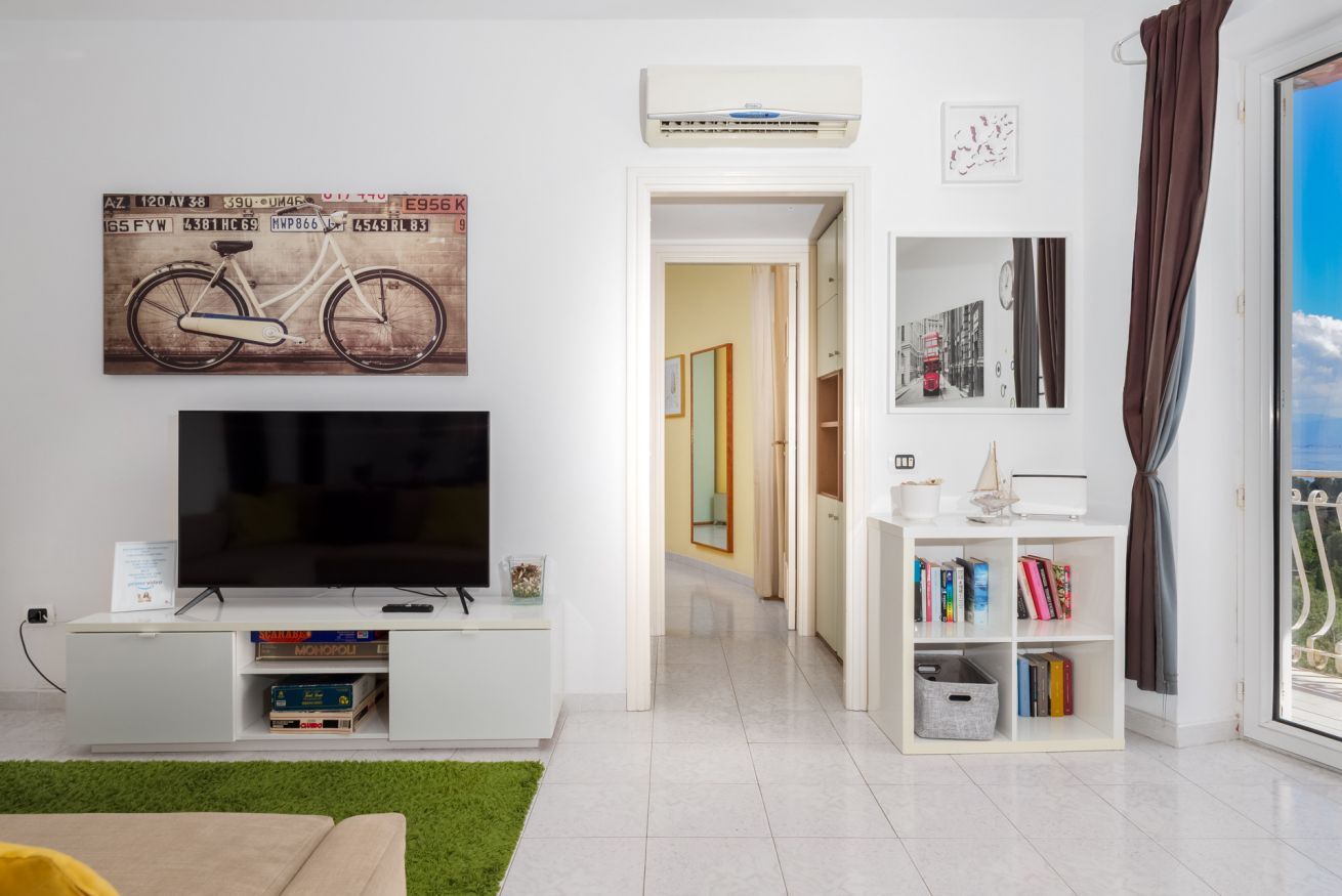 A modern living room with a flat-screen TV, a bookshelf, and a bicycle-themed artwork.