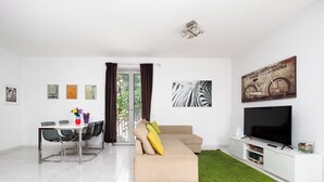 A modern living room with a sofa, TV, and artwork. - Casa Rosa is one of those places you choose for one specific detail… and then remember for everything else. That detail is the view: a balcony opening onto the Gulf of Naples with Mount Vesuvius in front, a wide, deep panorama that accompanies every mo (Sorrento)