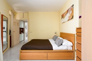 Een slaapkamer met een houten bed, een garderobe en een schilderij aan de muur.