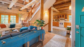 A rustic interior with a staircase, wooden beams, a kitchen, and a living area with a sofa and coffee table. - Blue Roof Lodge - Forest Getaway for Groups (Enumclaw)