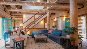 A cozy log cabin interior with a staircase, wooden furniture, and potted plants. - Blue Roof Lodge - Forest Getaway for Groups (Enumclaw)