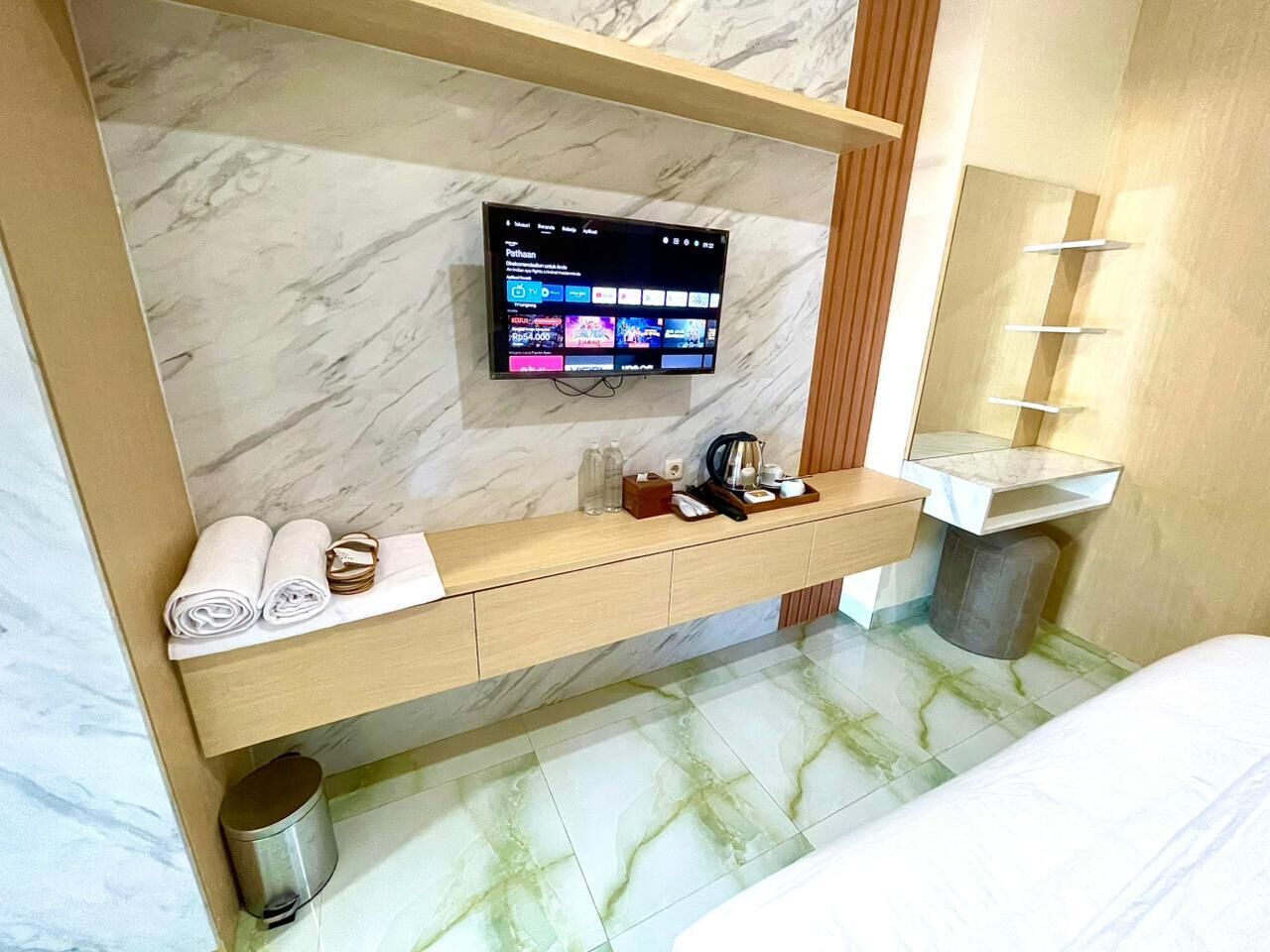 Un bagno moderno con un mobile vanità in marmo, una TV a parete, un porta asciugamani e un lavandino.