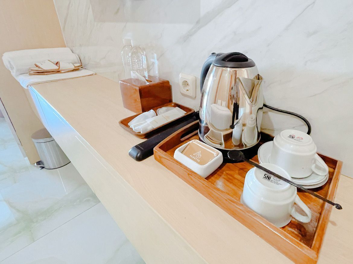 A hotel kitchenette with a coffee maker, cups, and a tray.