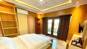 A hotel room with a bed, a desk, a chair, a wardrobe, and a window with curtains. - Alzetta Hotel by Abiza (Yogyakarta)