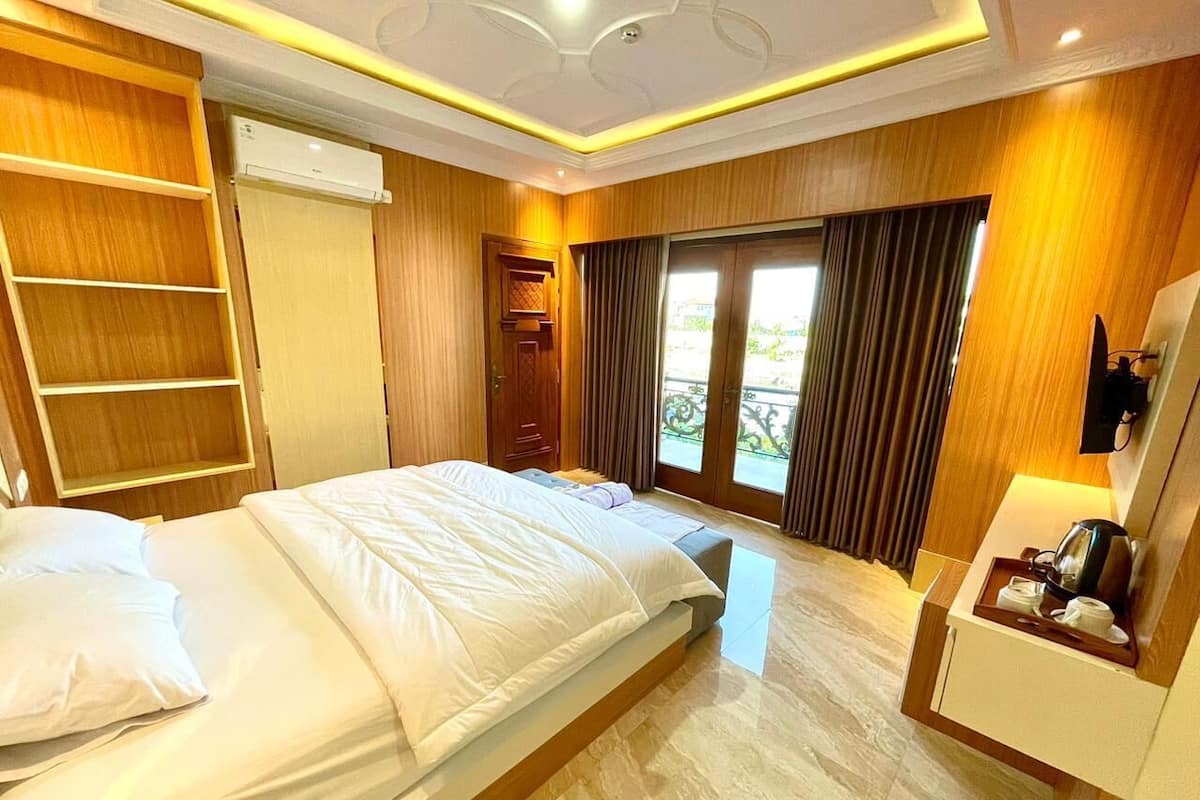 A hotel room with a bed, a desk, a chair, a wardrobe, and a window with curtains.