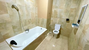 Un baño con bañera, inodoro y espejo.