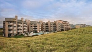 A coastal hotel with multiple floors, balconies, and a pool area. - Ocean Shores | Couple Coastal Retreat | Pool | 1BR (Ocean Shores)