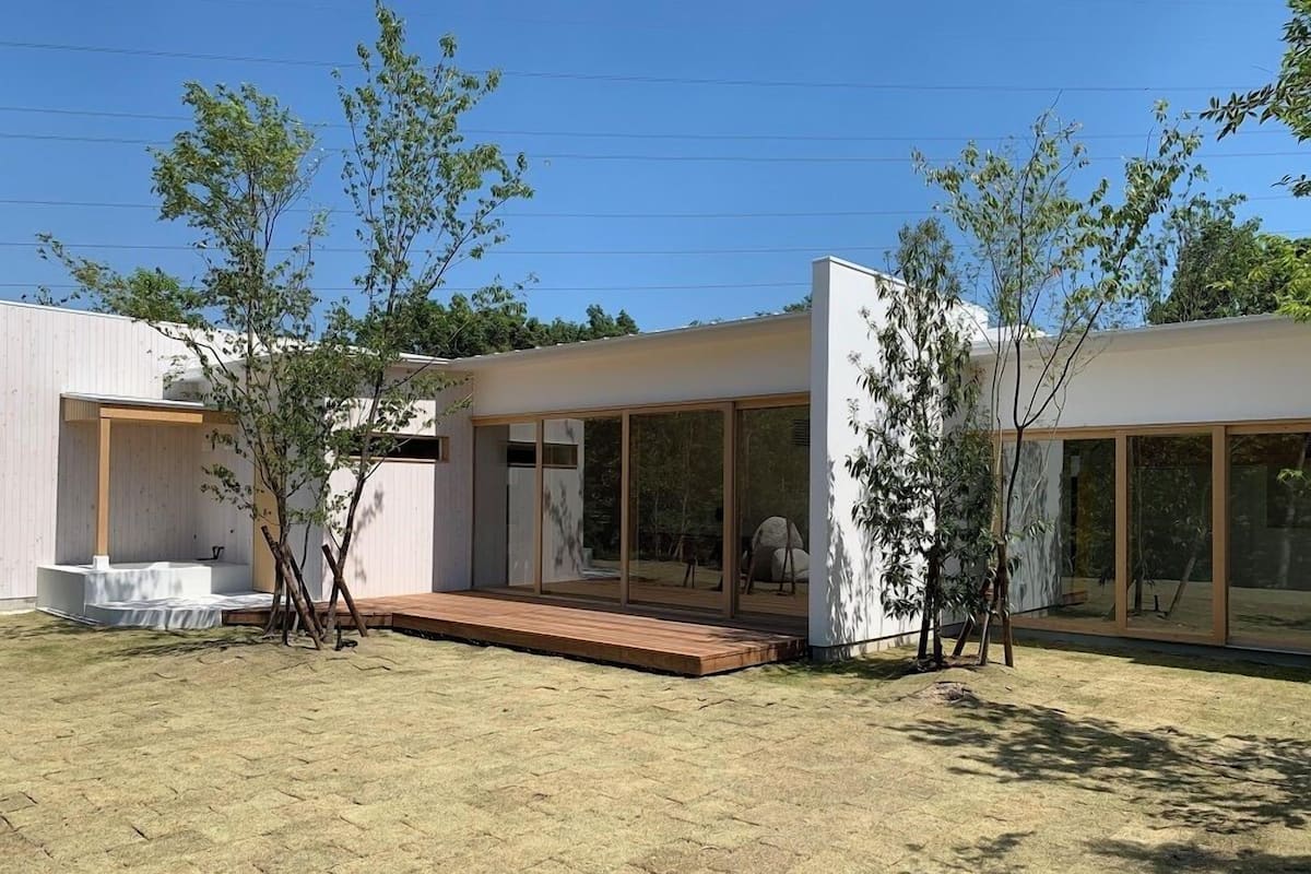 A modern house with a patio, large windows, and a wooden deck.