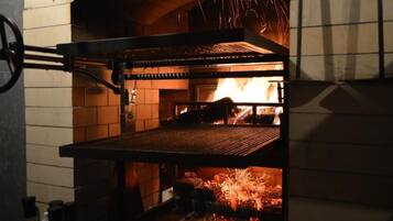 Un horno de ladrillo con una rejilla metálica en su interior, llamas visibles y una pared de ladrillo.