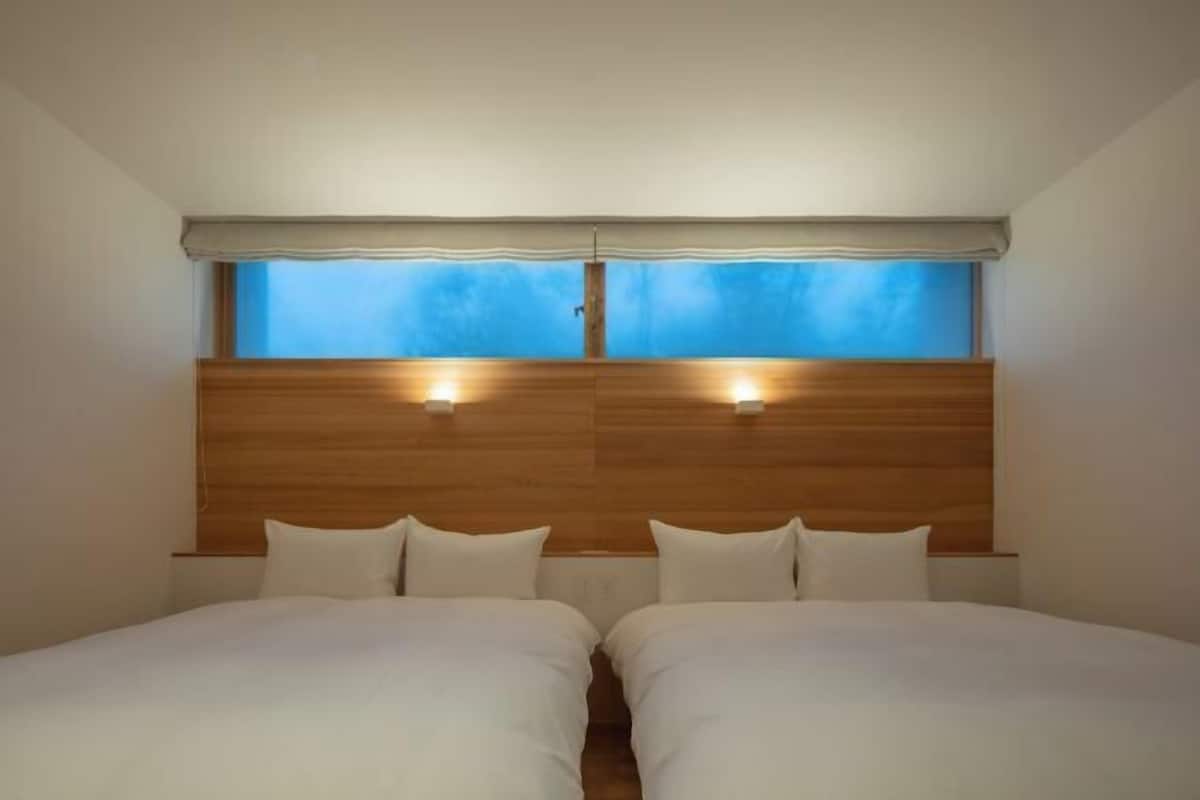 A room with two beds, a wooden headboard, and a window with a view.