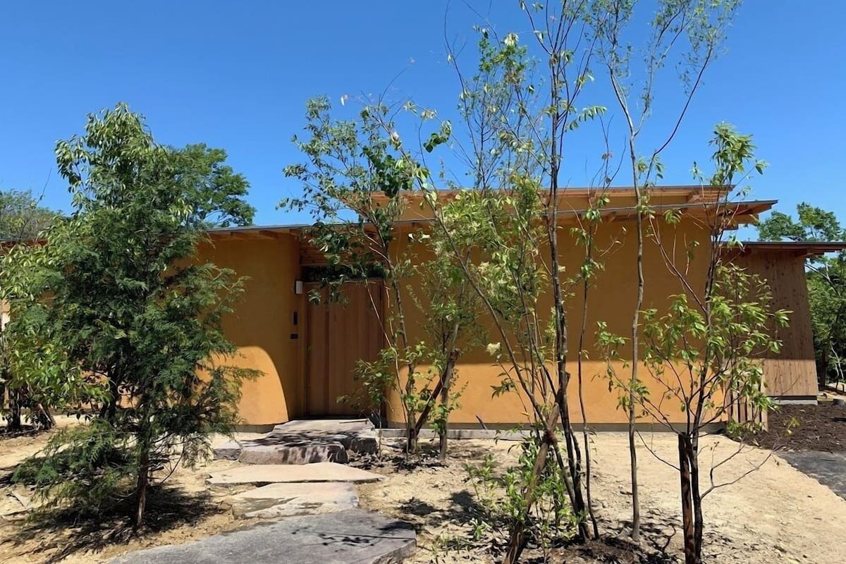 A building with a flat roof, surrounded by trees and a stone pathway.