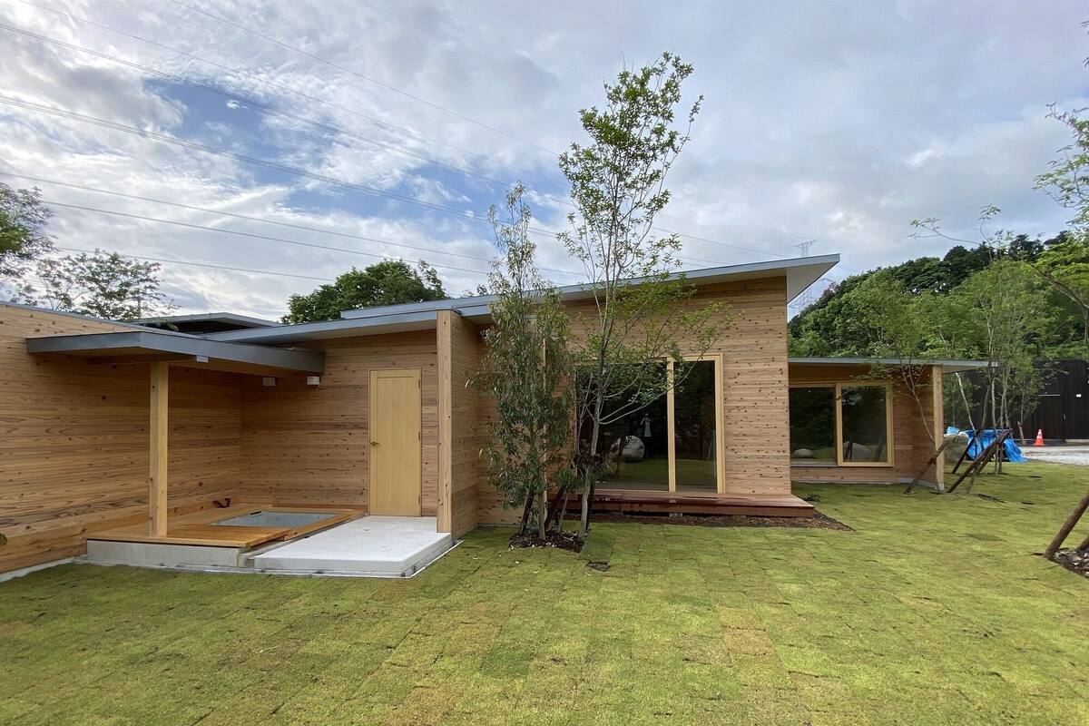 A modern wooden cabin with a flat roof, a small deck, and a glass door.