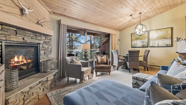 A cozy room with a stone fireplace, comfortable seating, and a large window. - New Listing! Whitefish Lake Condo, 16B, Hillside! (Whitefish)