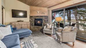 A cozy living room with a stone fireplace, a flat-screen TV, and comfortable seating. - New Listing! Whitefish Lake Condo, 16B, Hillside! (Whitefish)