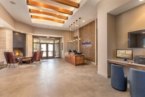A reception area with a fireplace, seating, a reception desk, and a TV screen. - Marble Falls | Group Lake Getaway | Pool + Lake | 3BR Sleeps 10 (Marble Falls)