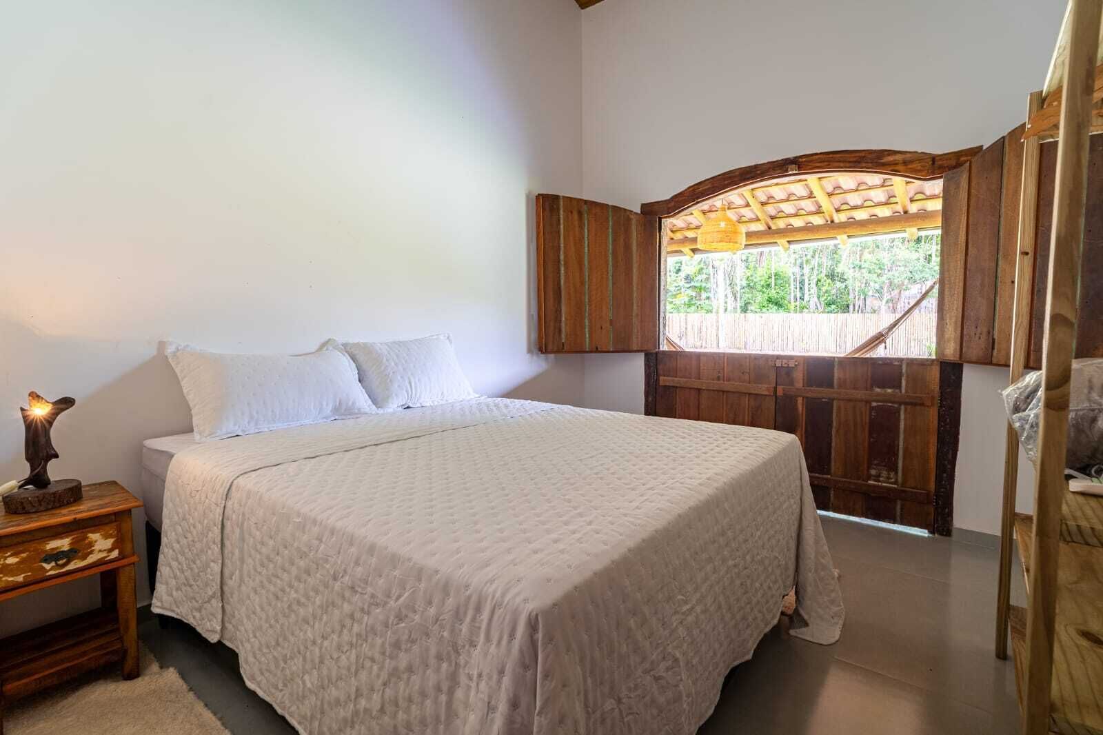 Une chambre à coucher avec un lit, une table de chevet avec une lampe et une porte en bois donnant sur l’ext érieur.