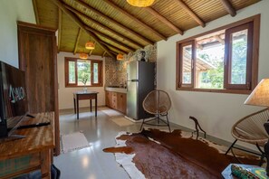 Eine rustikale Küche mit Holzbalken, einem Kühlschrank, einem Esstisch und einem Kuhfellteppich.