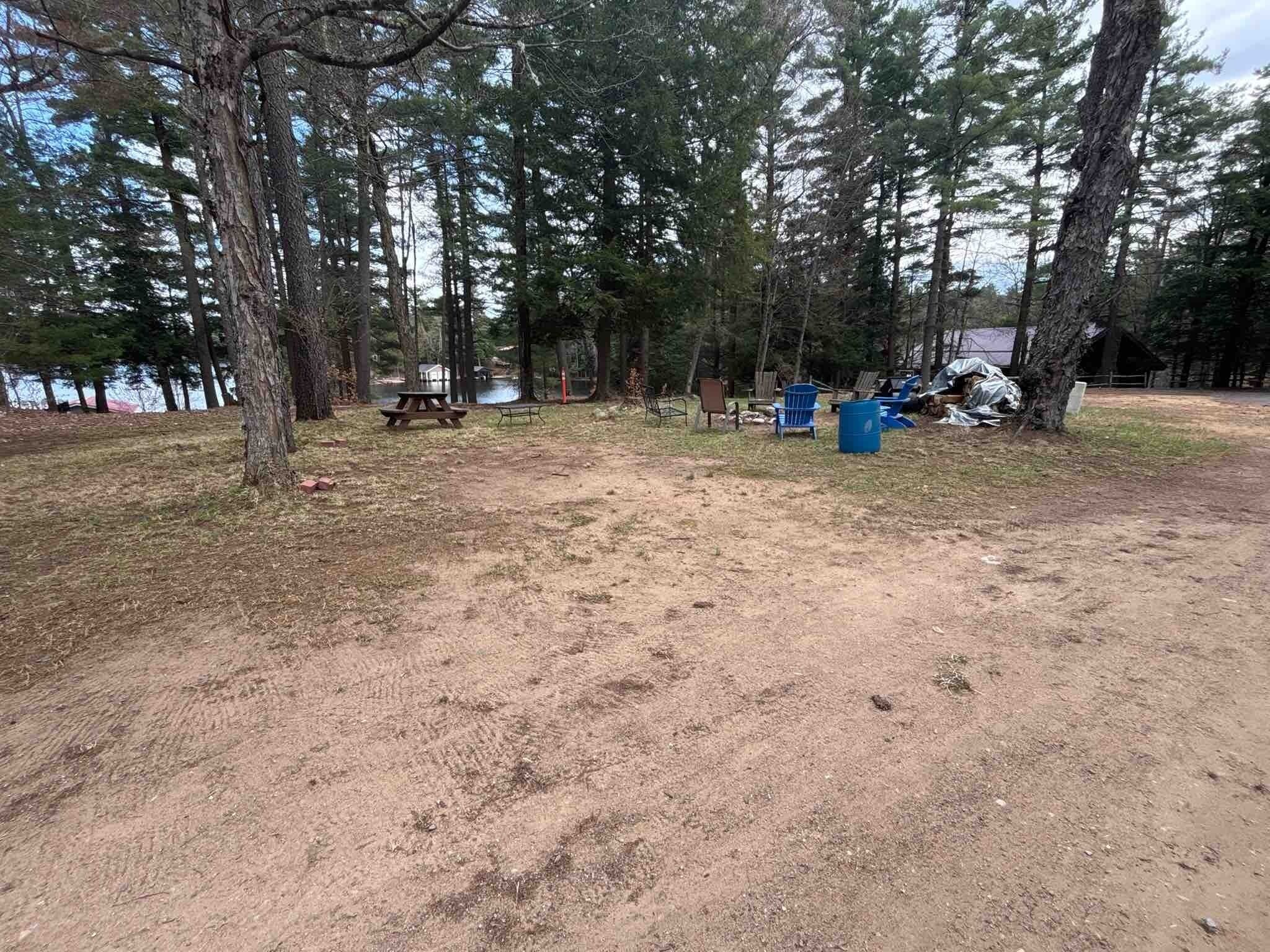 Ein Campingplatz mit Picknicktischen, blauen Stühlen und einem Picknicktisch am See.