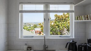 Un baño con una ventana grande, inodoro, lavamanos y cafetera.