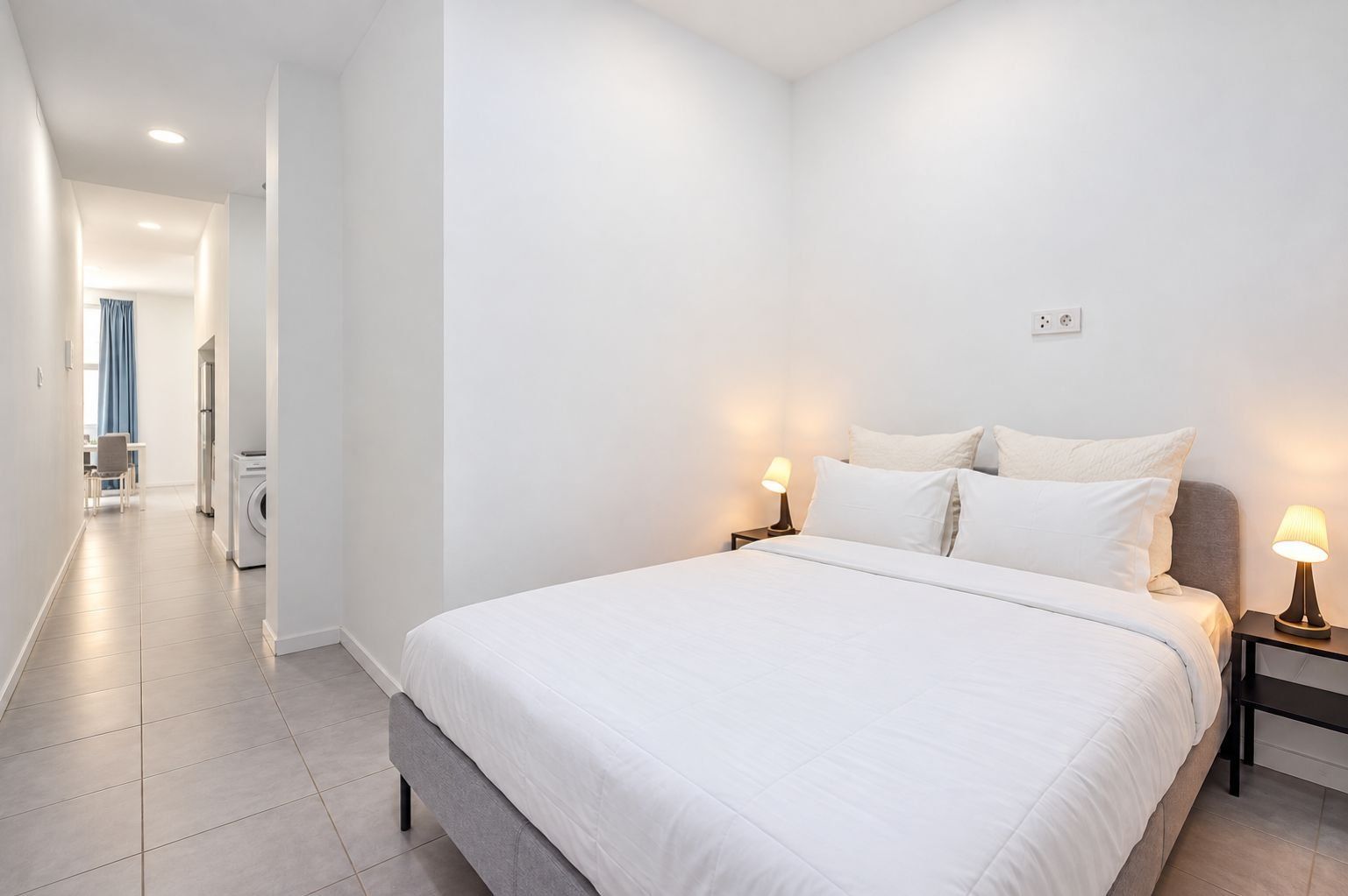 Un dormitorio con una cama grande, dos lámparas de noche y vistas al baño contiguo.