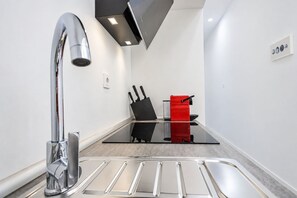 A modern kitchen with a stainless steel sink, a black and red appliance, and a glass countertop. - GuestReady - Charming studio in Malaga centre (Málaga)