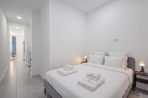 Ein Hotelzimmer mit einem Bett, zwei Nachttischen und einem Badezimmer im Hintergrund.