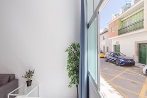 Ein Balkon mit Blick auf eine Straße, einem Blumentopf und einem Gebäude mit einer grünen Tür.