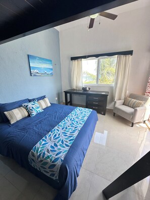 Un dormitorio con cama, escritorio, silla y ventilador de techo.