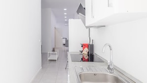 A modern kitchen with a stainless steel sink, a coffee machine, and a small white table. - GuestReady - Cosy studio in Malaga centre (Málaga)