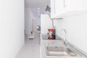 A modern kitchen with a stainless steel sink, a coffee machine, and a small white table. - GuestReady - Cosy studio in Malaga centre (Málaga)