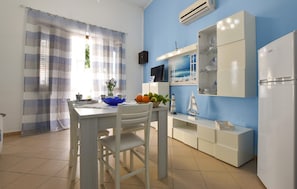 Eine Küche mit einem weißen Tisch, Stühlen, einer blauen Schüssel und einem weißen Kühlschrank.